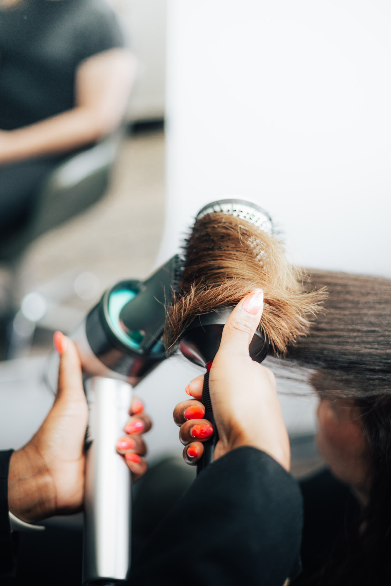 DLuxe stylist wrapping hair around a round brush during a blowout